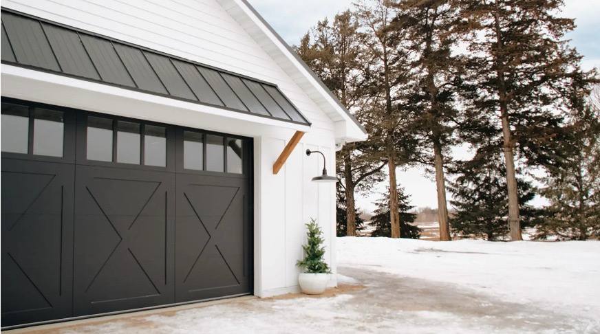 Black carriage-style garage door on a white modern farmhouse