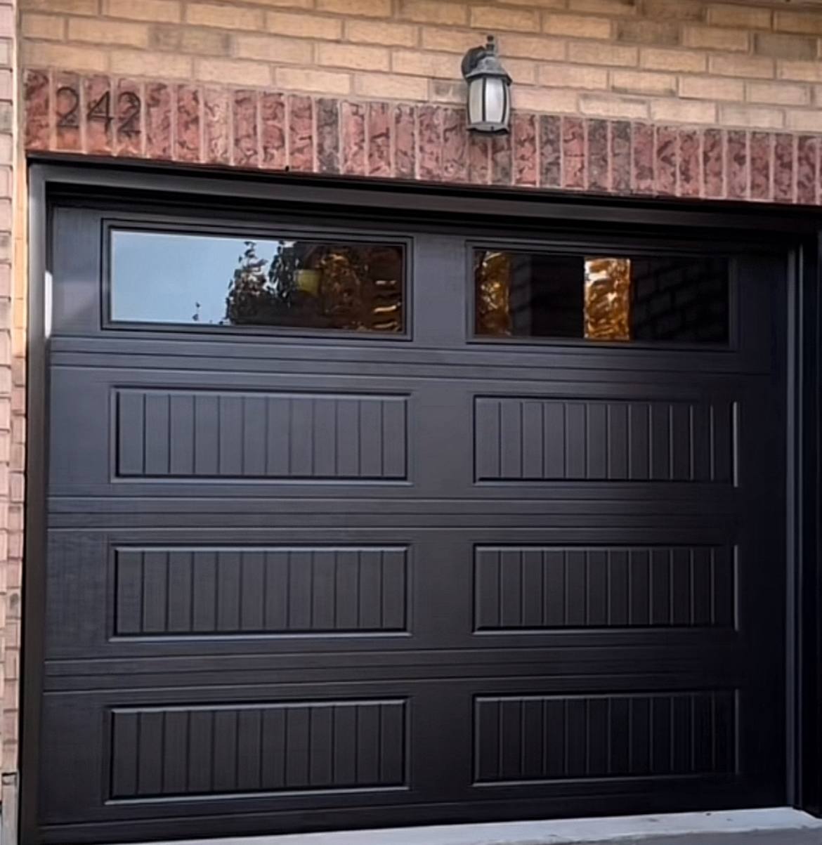 Finished black residential garage door on a brick home in the GTA